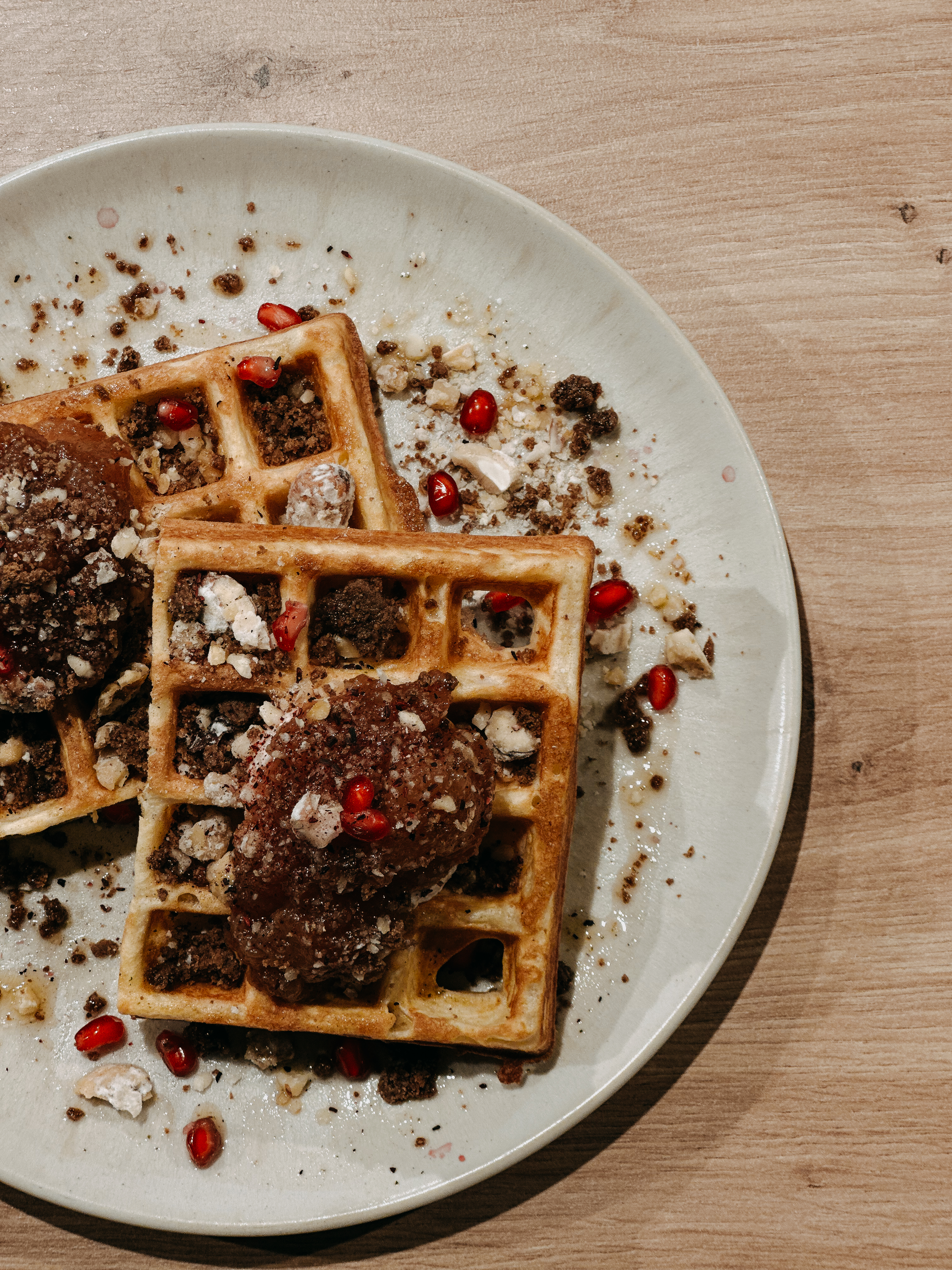 Ein Teil unserer Waffelbande – die süße Chailotta. Eine Waffel mit Chai-Creme, Bratapfelkompott, Lebkuchen-Crumble, gebrannten Nüssen, Granatapfel & Kräuteröl – serviert auf unserem beigen Teller.